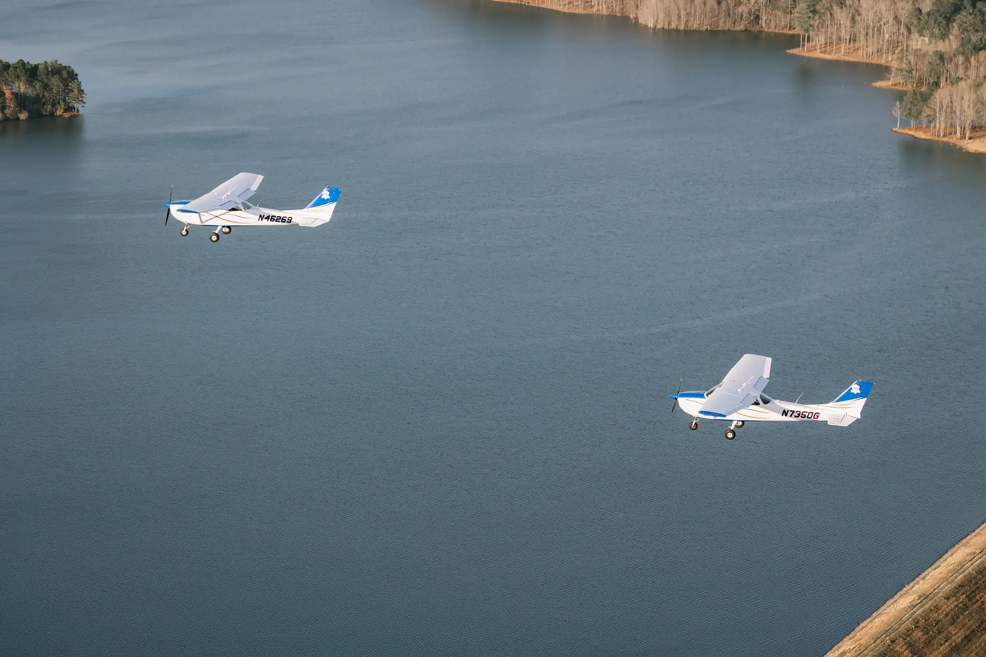 Two Cessna 172 aircraft flying over a Georgia lake