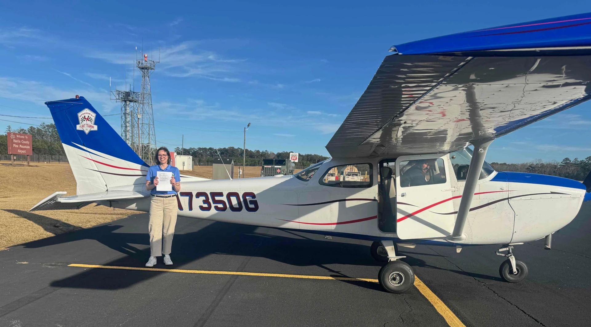 Pilot holding a certificate in front of a Speedway Flight Training aircraft